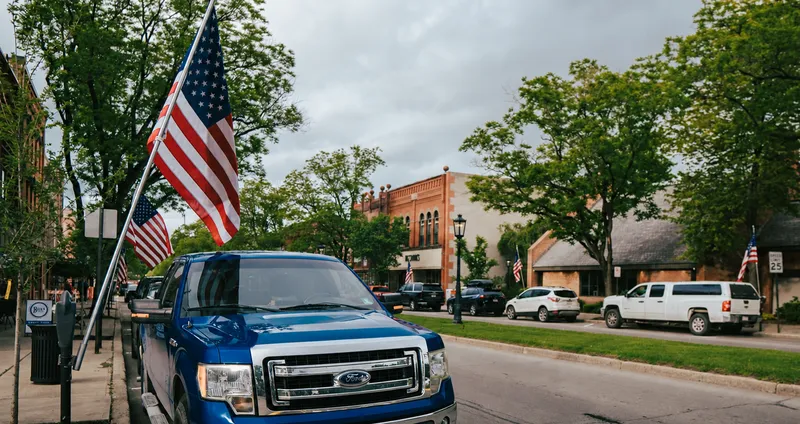 A pickup truck parked on a small-town main street lined with American flags