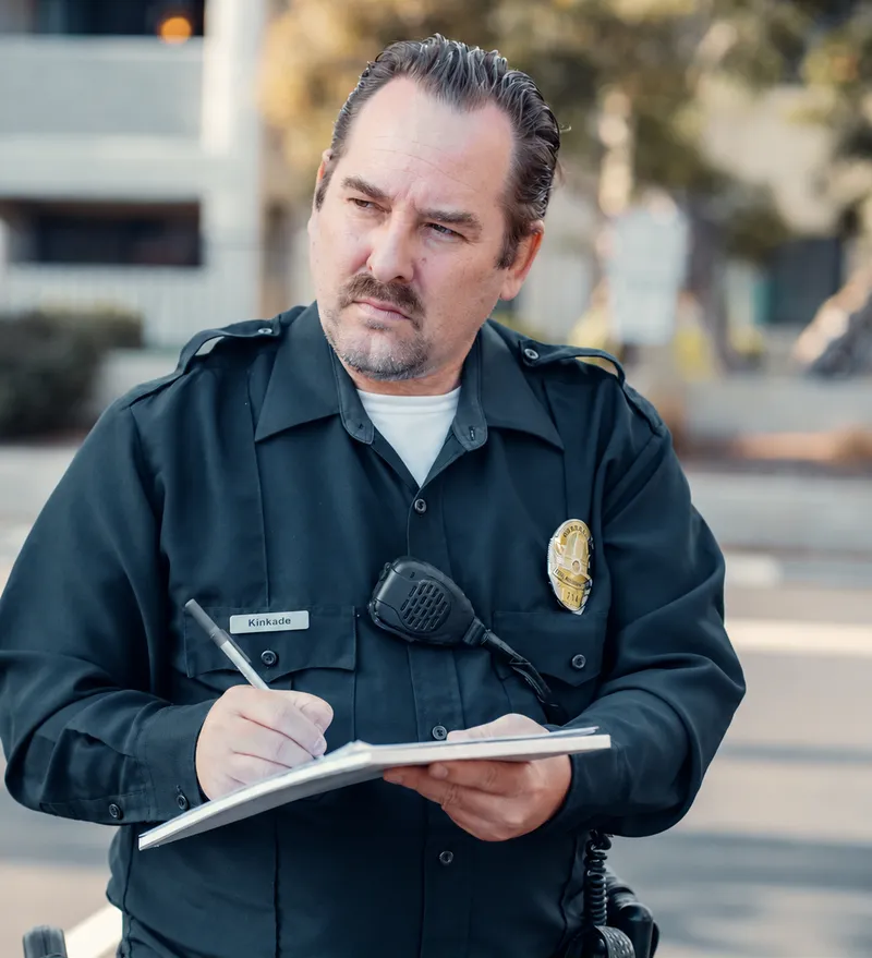 A uniformed officer taking notes on a notepad