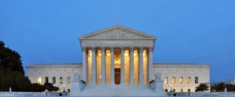 The U.S. Supreme Court building lit at dusk